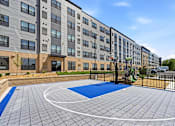 Thumbnail 1 of 22 - A basketball court is located in front of a multi-story apartment building.